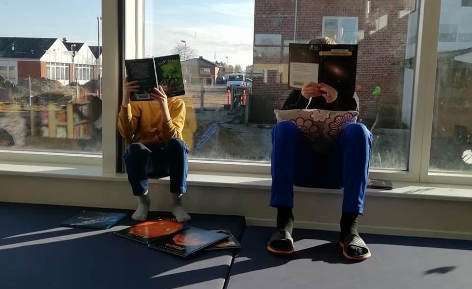 Billede af børn der sidder og læser i vindueskarmen